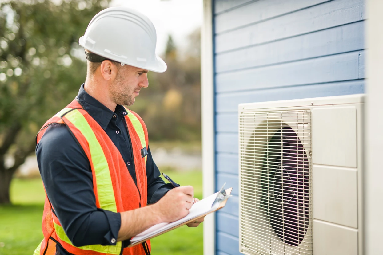Un technicien travaillant sur la climatisation ou la pompe à chaleur d'une unité extérieure