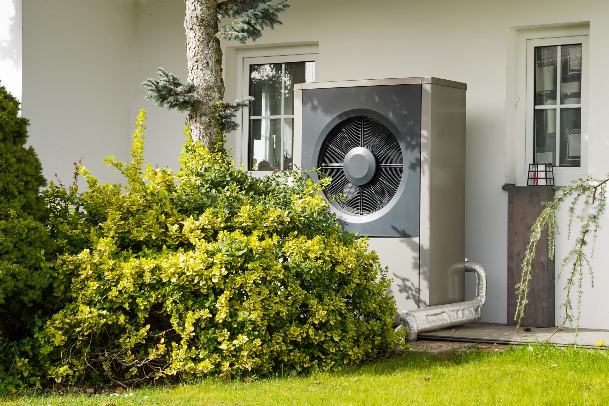 Sc&egrave;ne ext&eacute;rieure r&eacute;sidentielle avec pompe &agrave; chaleur air-eau install&eacute;e sur terrasse moderne
